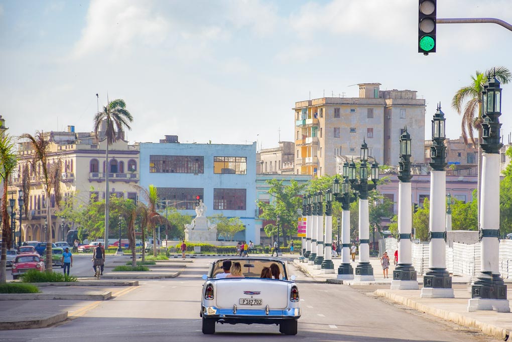 A car drives down a road in the old city of Havana, Cuba