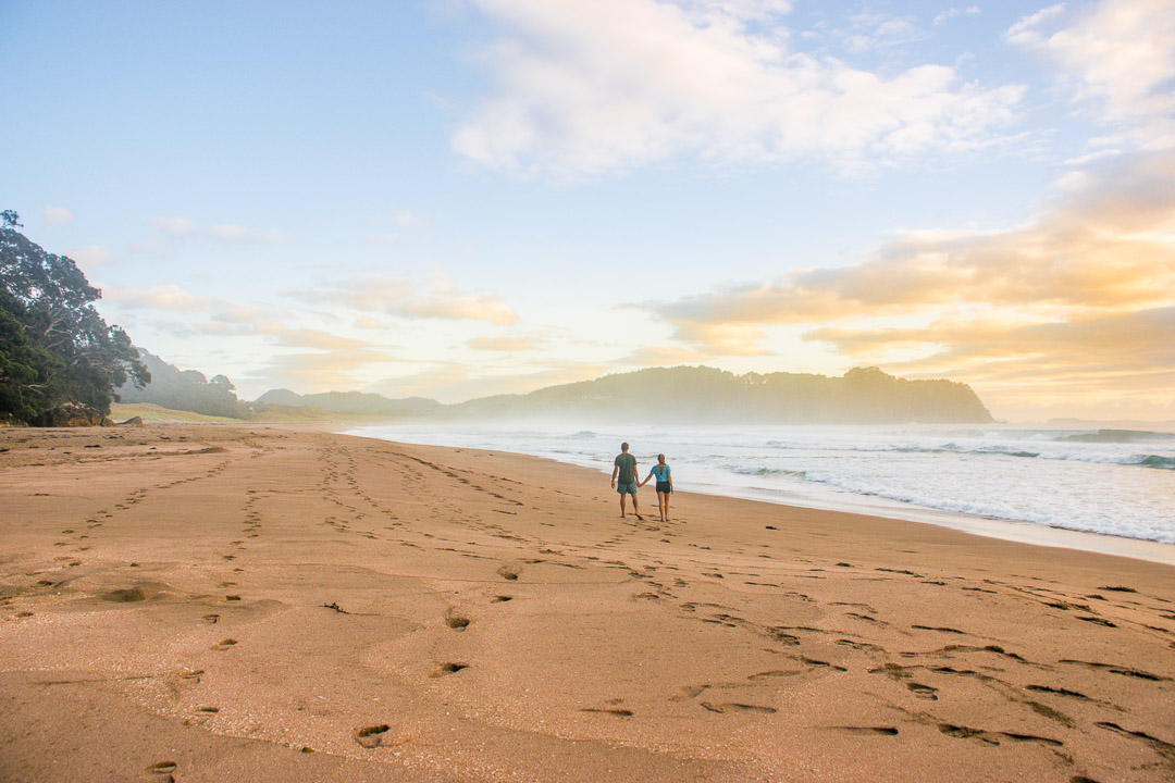 Two people walk along Hot Water Beach, New Zealand