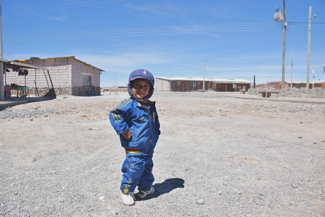a cute kid posing for the camera on the slat flats in bolivia