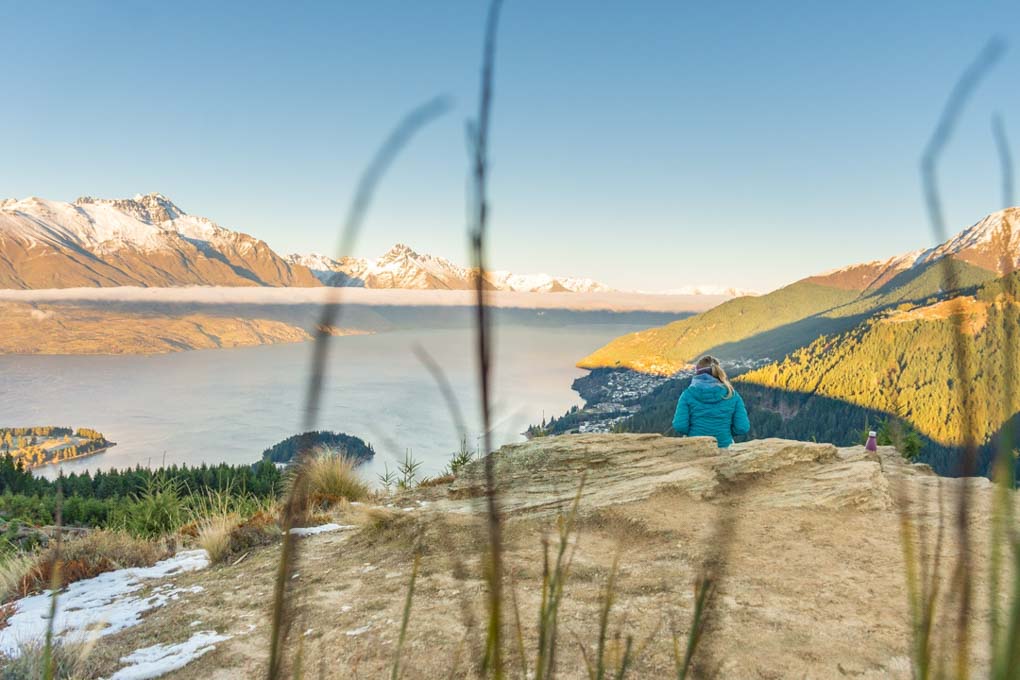 A woman watches a sunrise from the top of Queenstown Hill in Queenstown