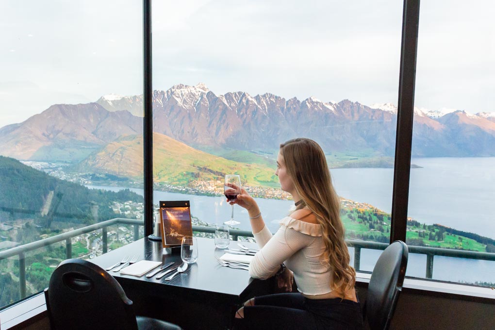 Bailey sits at our table with a glass of wine at the Stratosfare Restaurant in Queenstown