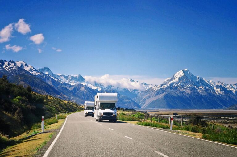 two motorhomes drive on a road towards Mount Cook in NZ on a sunny day