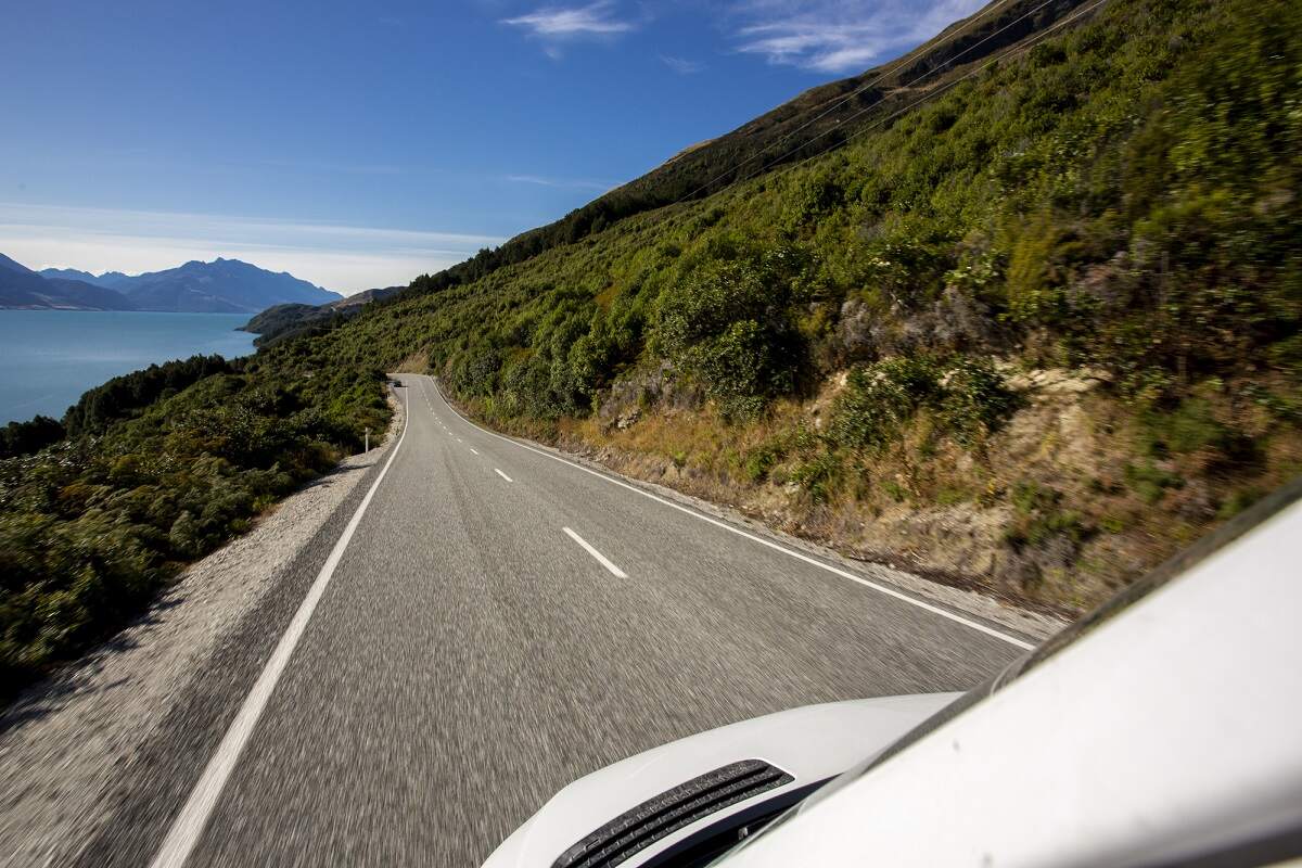 campervan drives down a scenic road in New Zealand