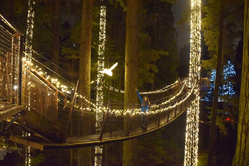 A lady poses for a photo on the Capilano Suspension Bridge Walk at night