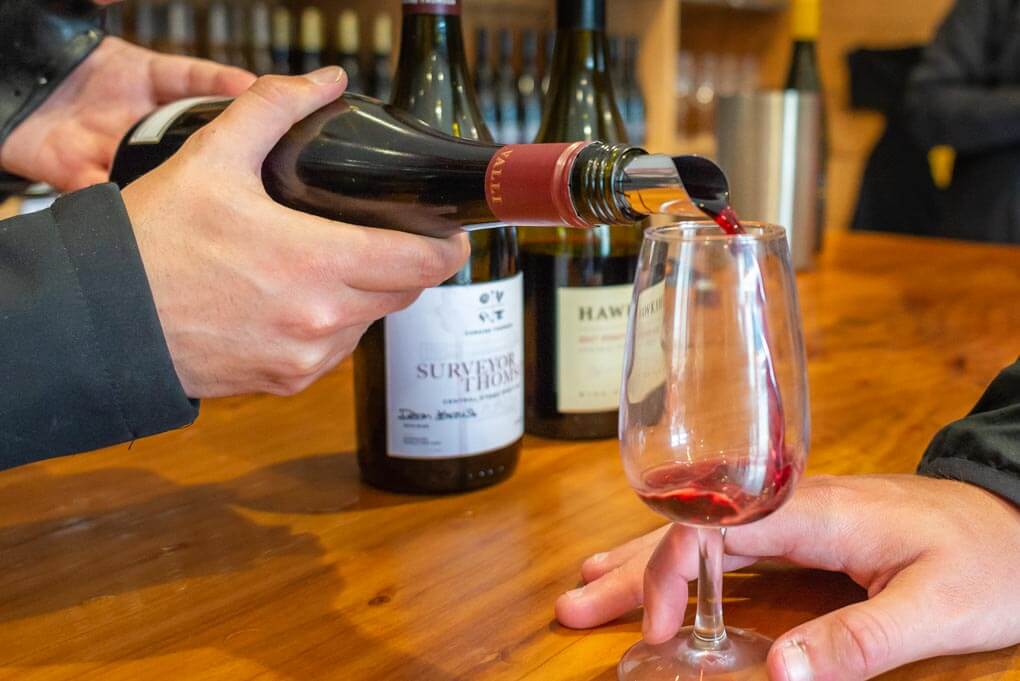 Pouring wine into a glass at a Queenstown winery