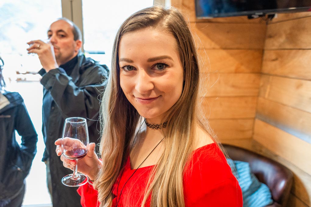 Bailey hiding her tasting glass of wine and smilling at the camera at kinros Winery