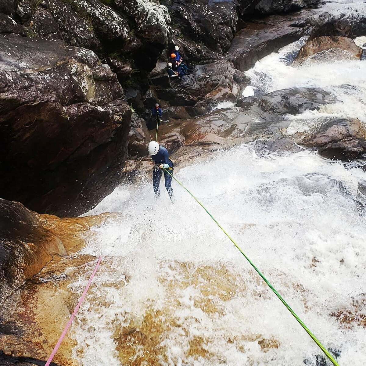 person rappelling down a waterfall