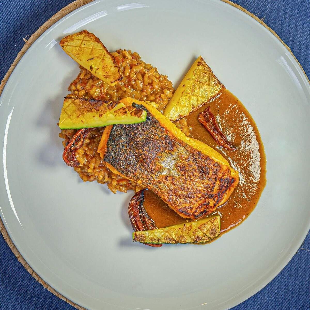 a fish dish with rice and sauce and yuca arranged on a white place