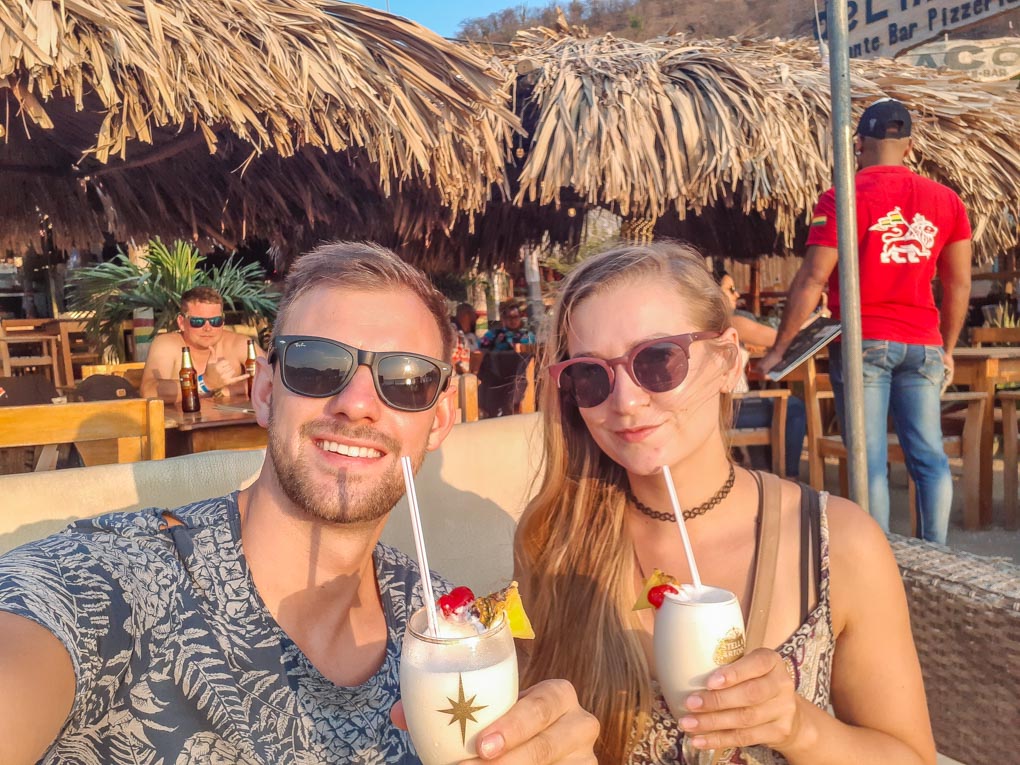 Bailey and Daniel drink cocktails as the sun sets on Taganga Beach near Santa Marta