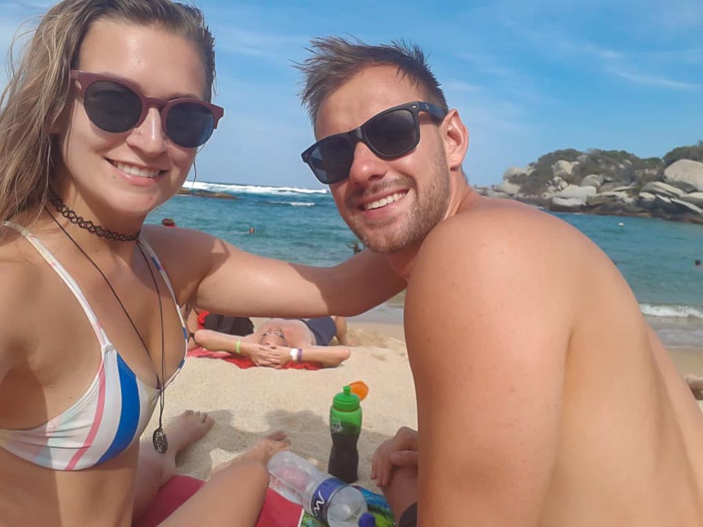 Bailey and Daniel sit on a beach in Tayrona National Park