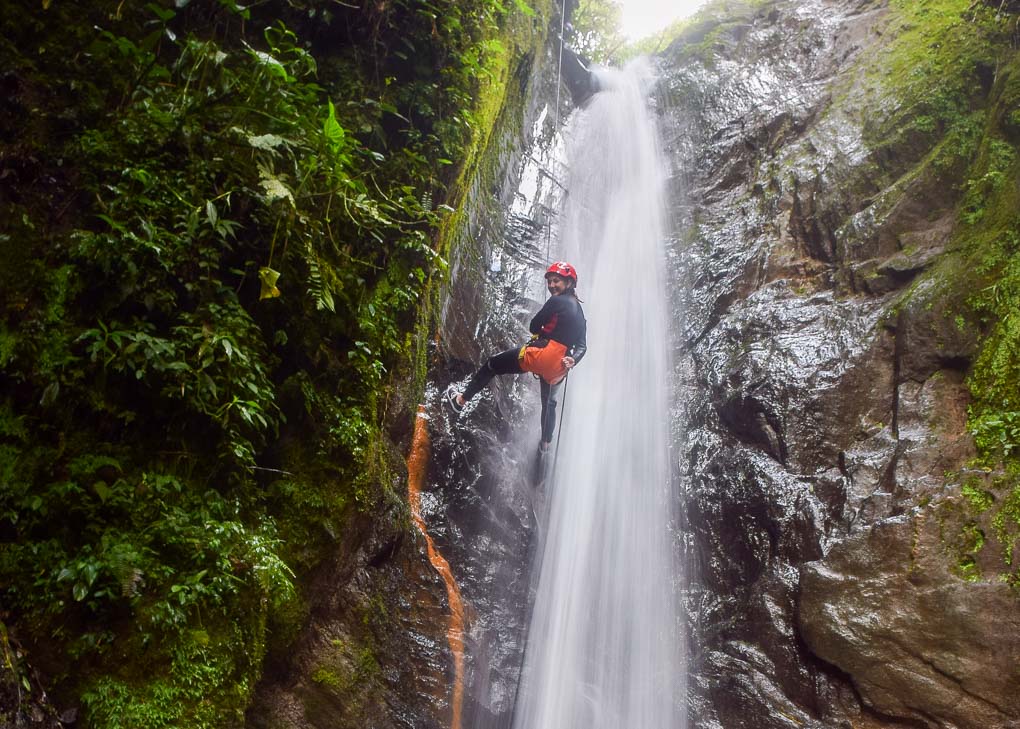 A lady repels down a waterfall while Canyoning in Banos, Ecuador