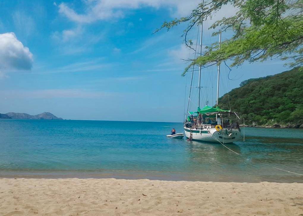 A sail boat is anchored up at a beach in Tayrona National park after sailing from Santa Marta