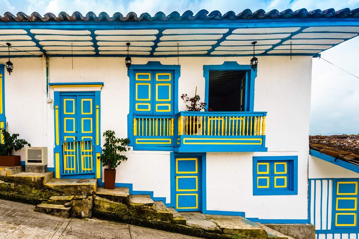 a white and blue colorful colonial style house on a street in Salento