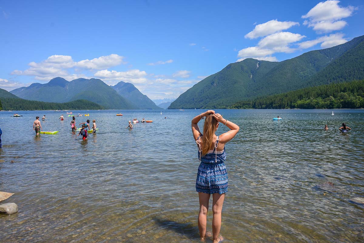 A lady stands in the water at Alouette Lake with mountain views in BC