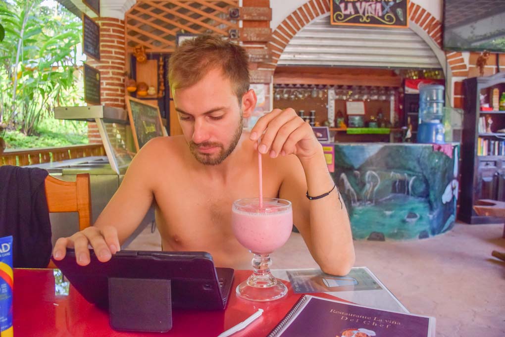 man drinks a cocktail while on the computer
