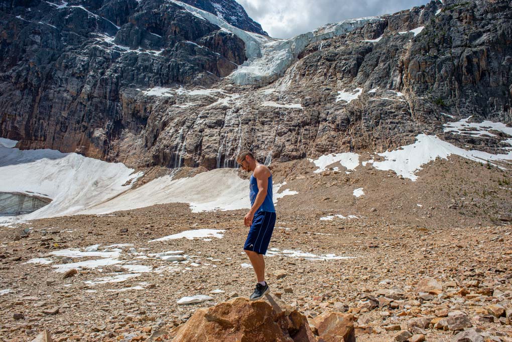 A man stands below Edith Cavell Mountain looking at the glacier