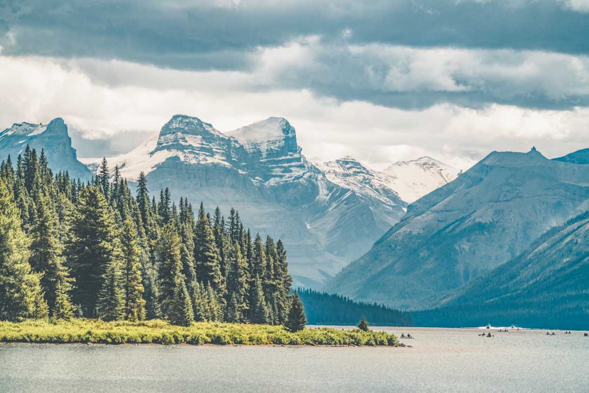 People kayak on Maligne Lake with a mountain backdrop
