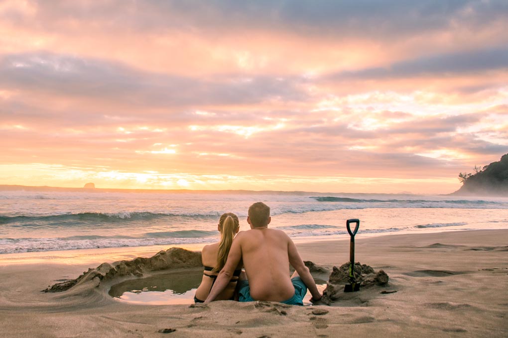 A couple relax at Hot Water beach in New Zealand