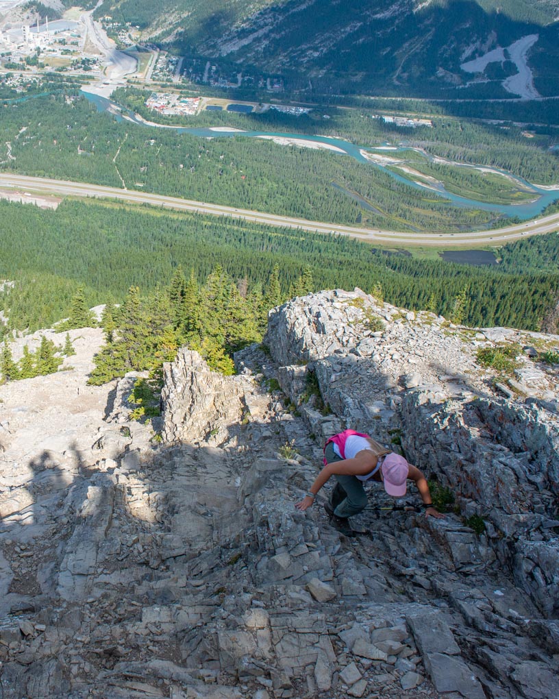 A lady on her hands scrambles up Heart Mountain on the Heart Mountin loop