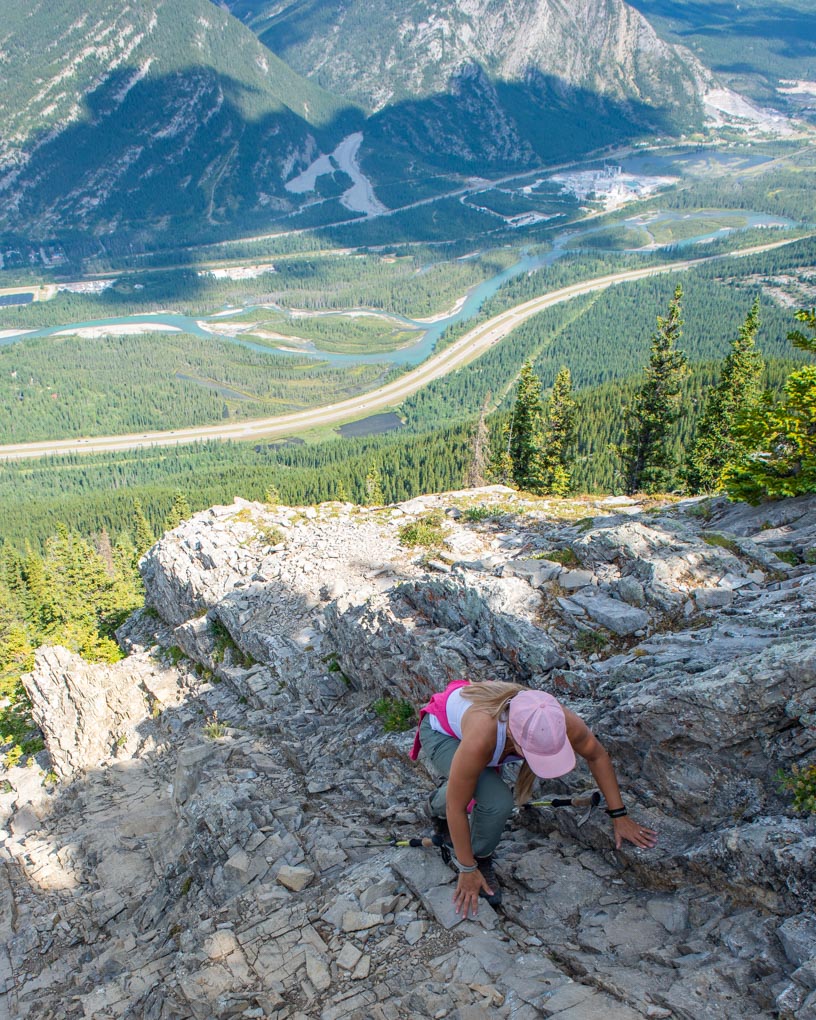 A lady on her hands climbing up Heart Mountain Trail