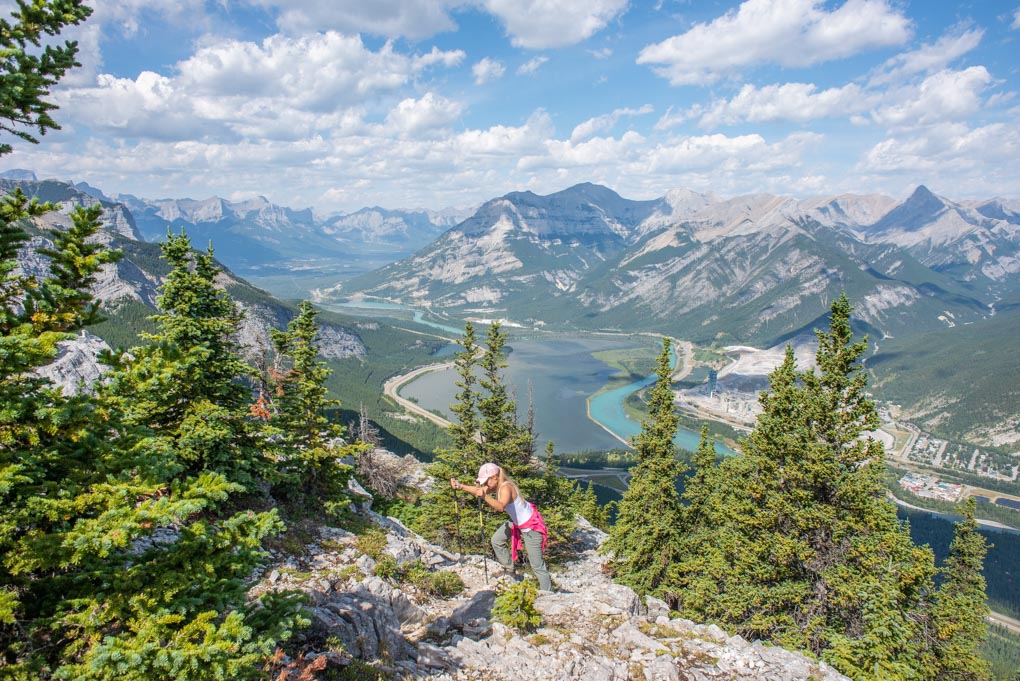 A lady climbs up rock on the Heart mountain hike near Canmore, Alberta