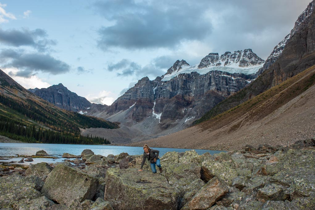 A lady climbs over a boulder on the Consolation Lakes Trail near Lake Moraine