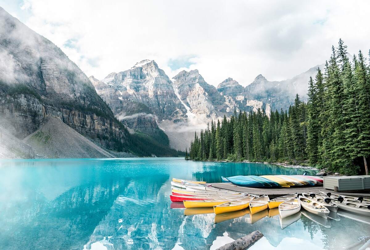 canoes on the edge of Moraine Lake with ten peaks covered in clouds