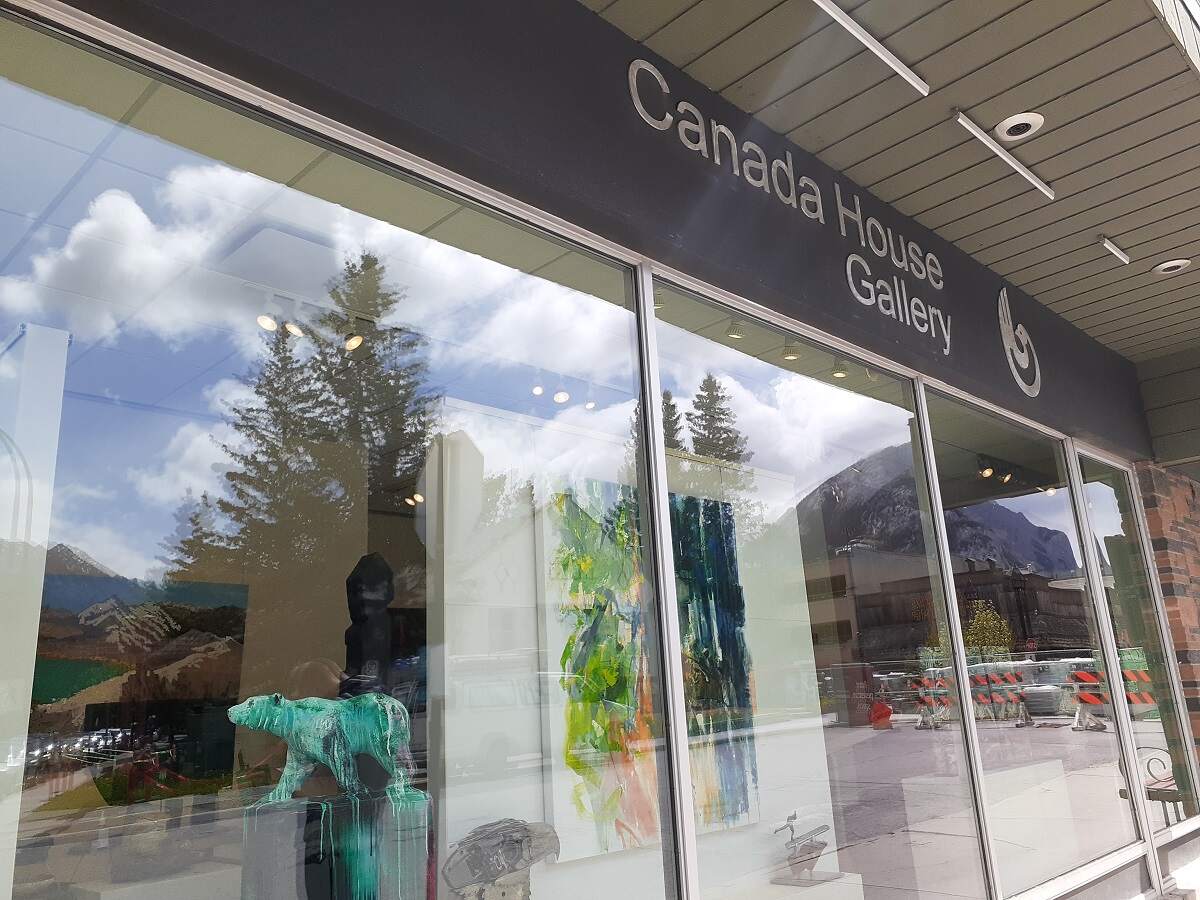 the outside of Canada House Gallery in Banff with art pieces seen through the window