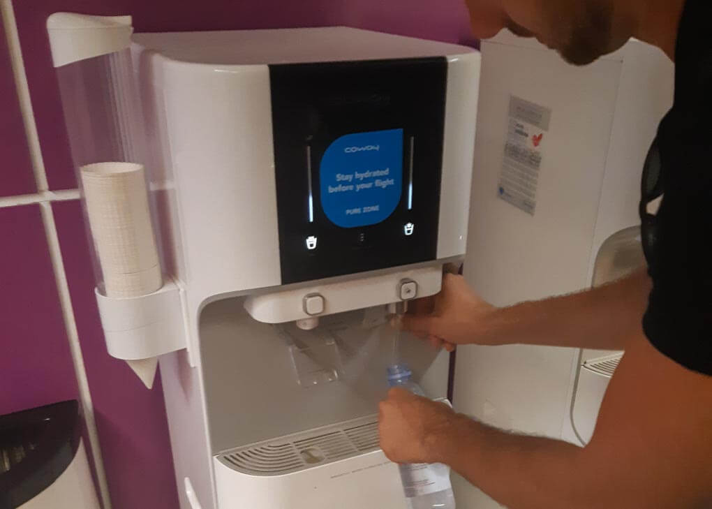 A man fills his water bottle at an airport fountain