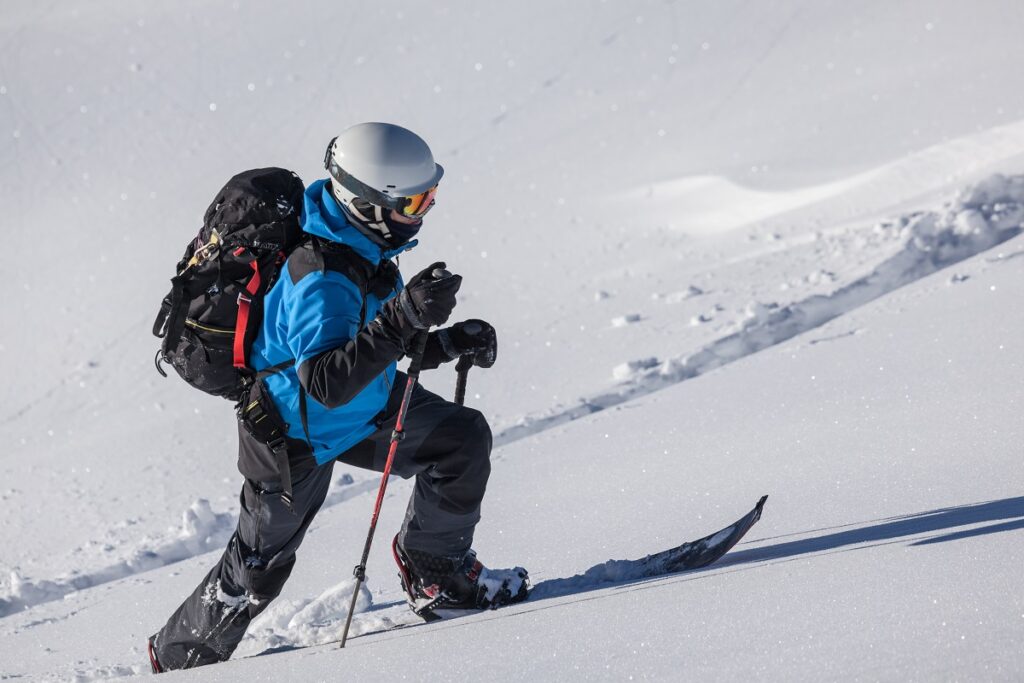 man climbing in skies in the backcountry snow