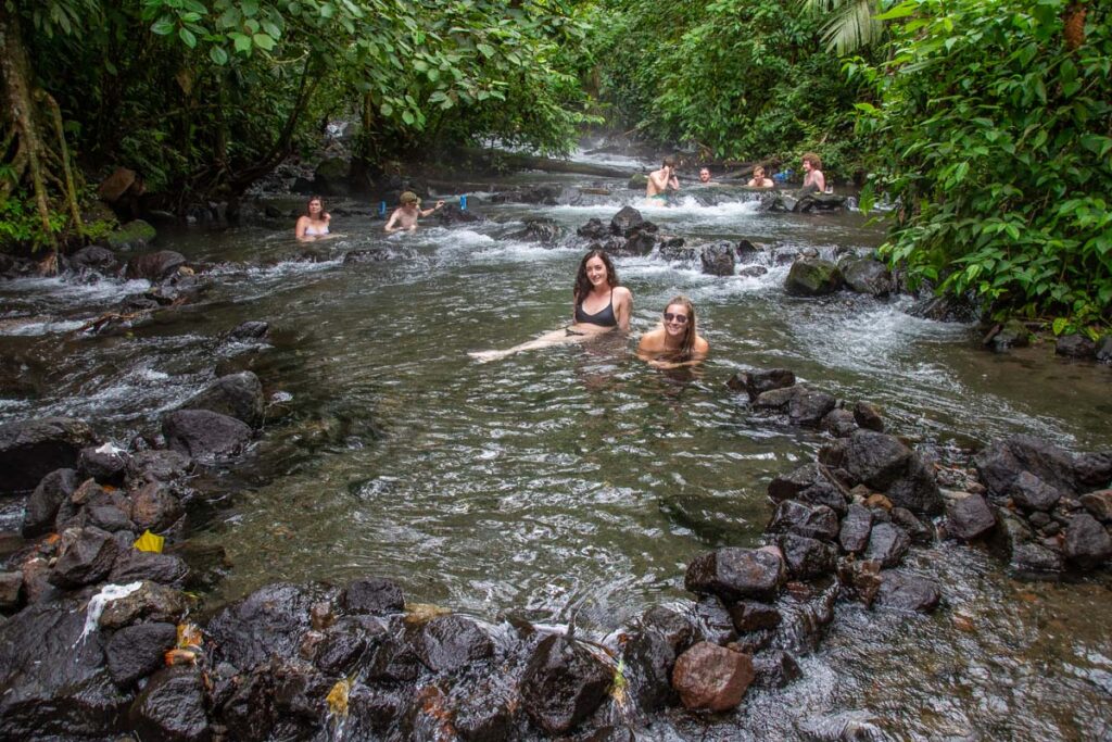 Two people relax in the 4. Relax at the free Natural Hot Springs River in La Fortuna