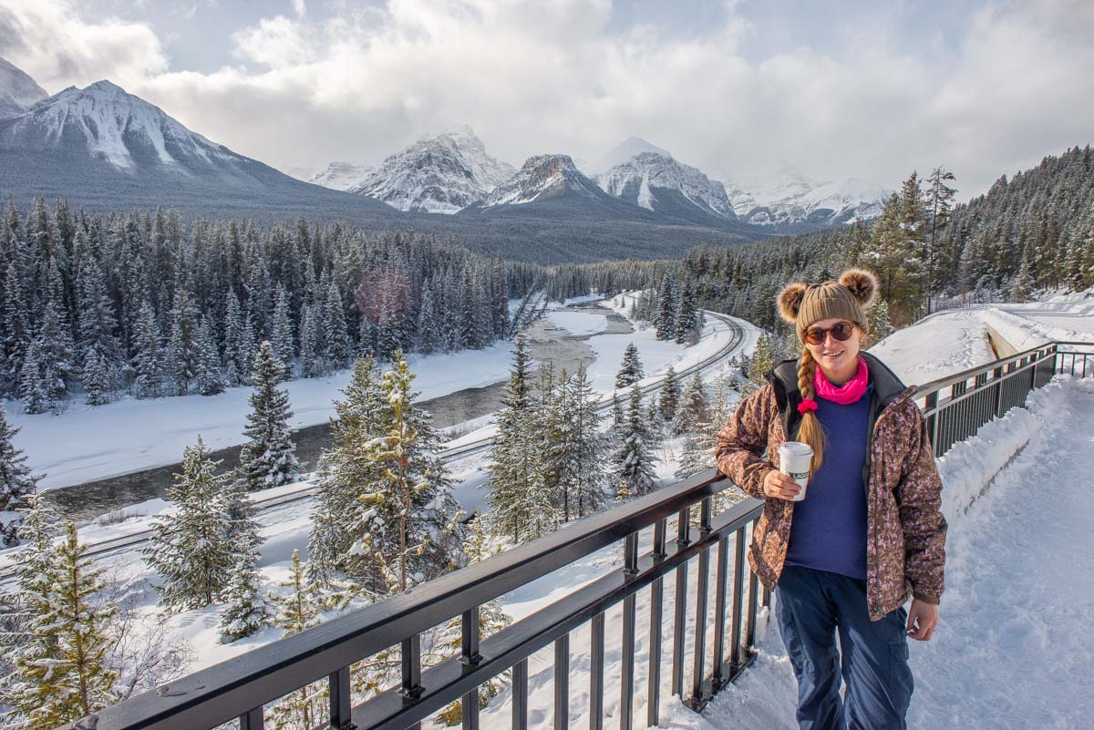 A lady poses for a photo at Morant's Curve on the Bow Valley Parkway during winter in Banff National Park