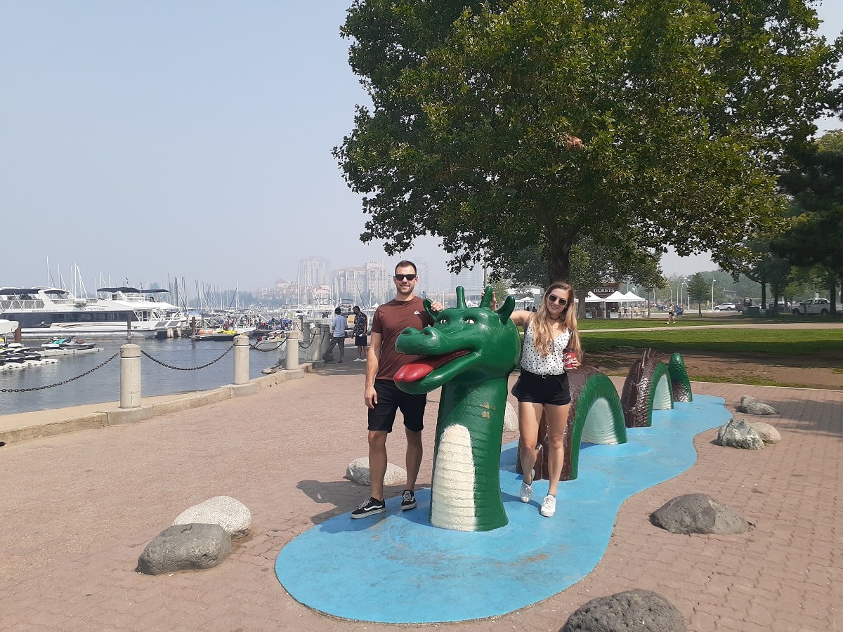 a couple taking a photo with the famous ogopogo statue in downtown Kelowna