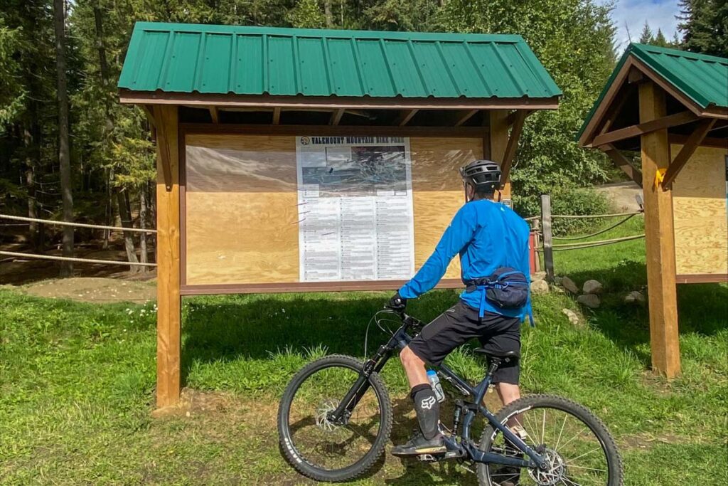A man reading a sign at the Valemount Mountain Bike Park