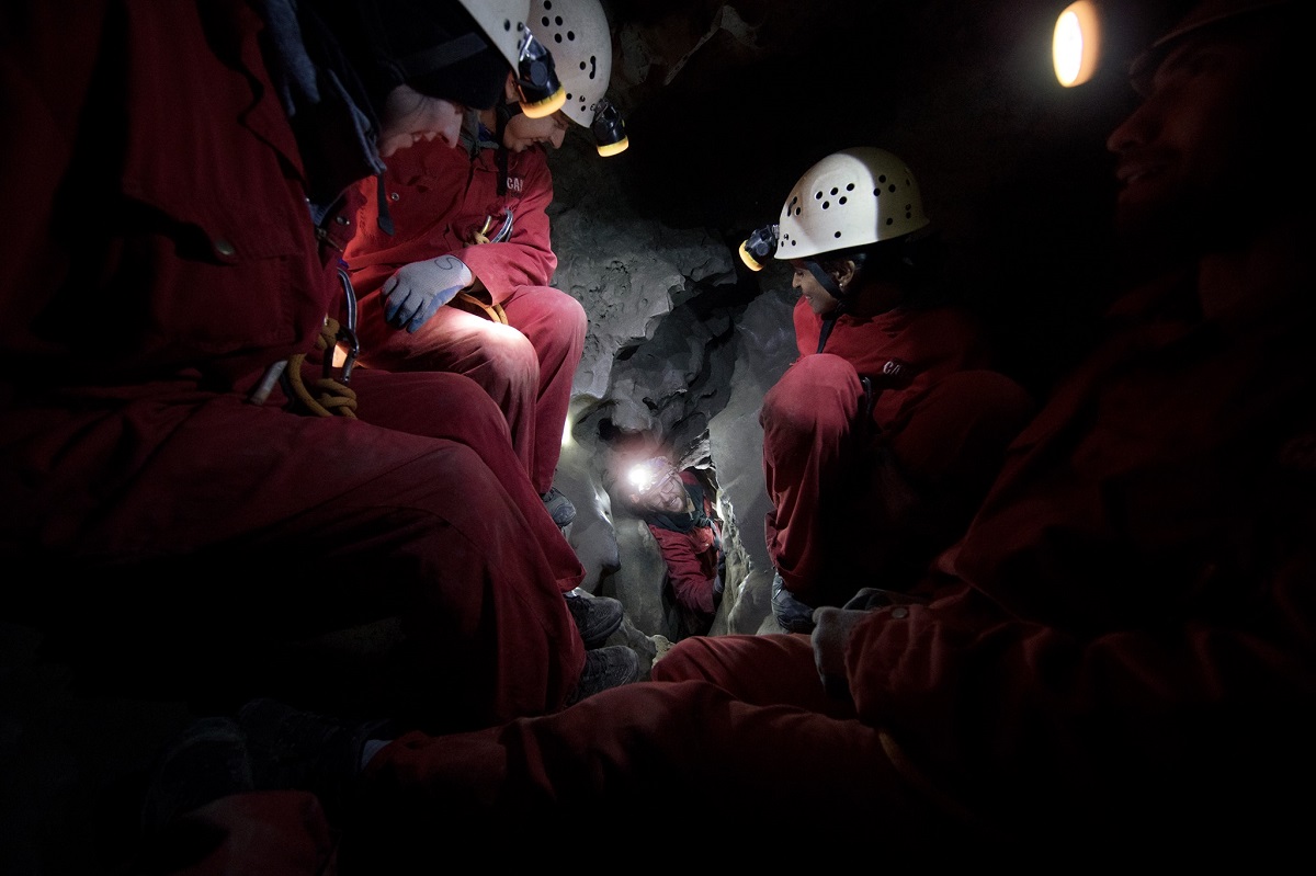 group of people staring down a cavern in a narrow cave in Canmore, Alberta