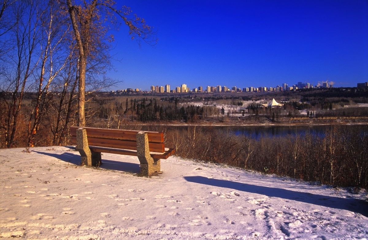a bench in the snow along the edmonton river valley
