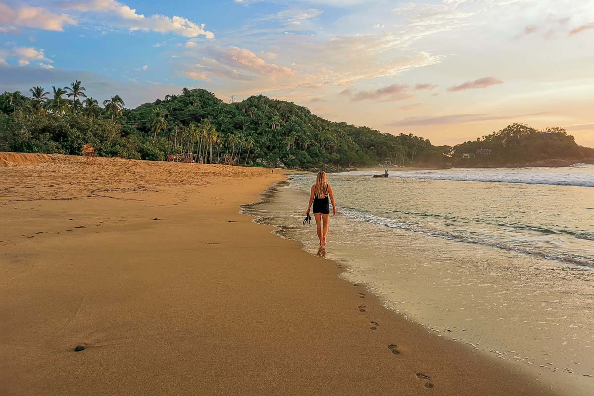 A lady walks along San Pancho Beach, Mexico