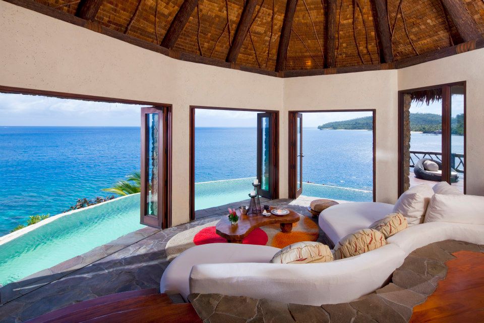 Views from a daybed at Laucala Island Resort looking out at an infinity pool and the ocean.