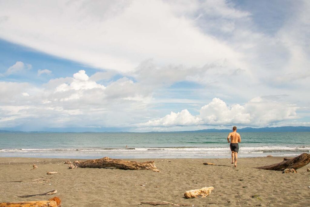 a man runs into the water at Playa Plataneres, Puerto Jimenez