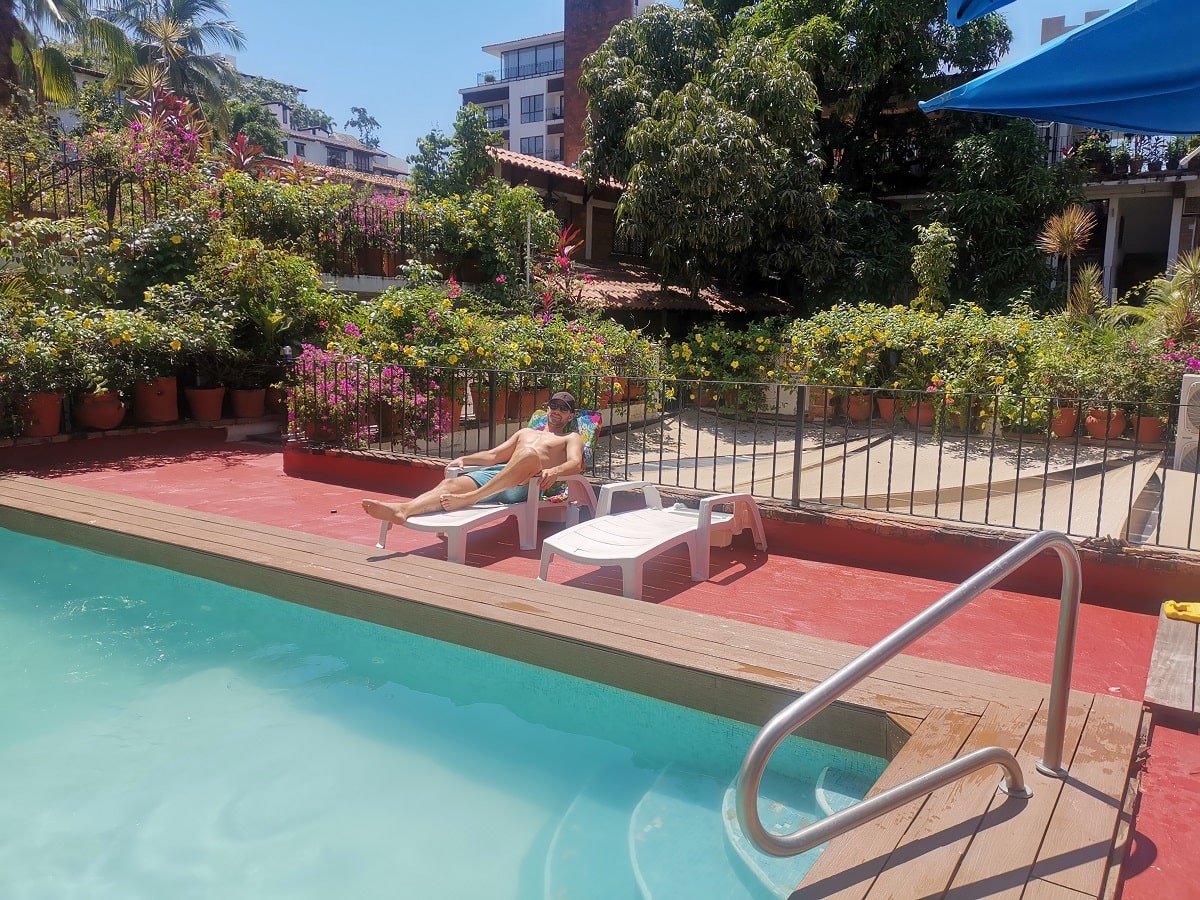 man laying by the pool in the garden at Posada de Roger hotel in Puerto Vallarta