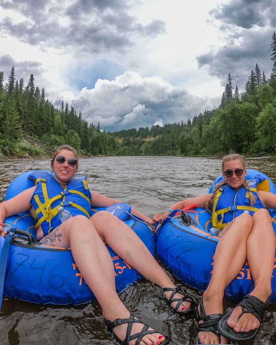 two women float down the Pembina River on tubes