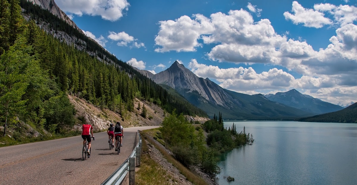 three people cycling along a remote road in Jasper National Park