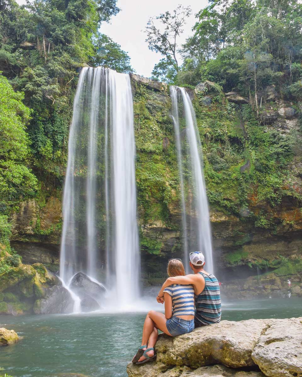 A couple sit in front of Misol Ha Waterfall near Palenque, Chiapas, Mexico