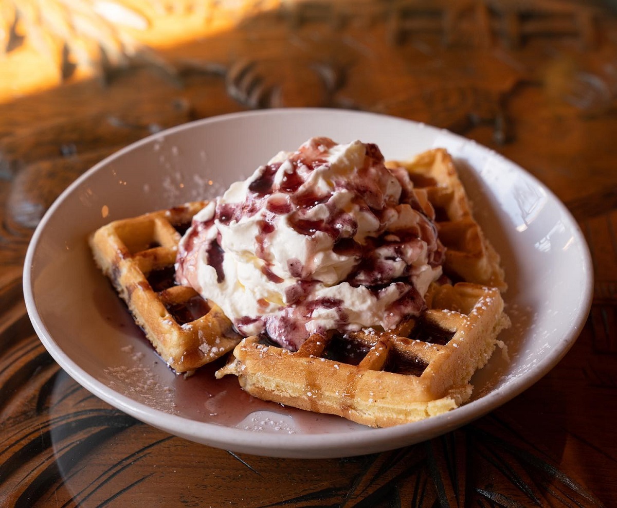 a plate of three waffles covered in whipping cream and berries from the Sugarbowl restaurant in Edmonton