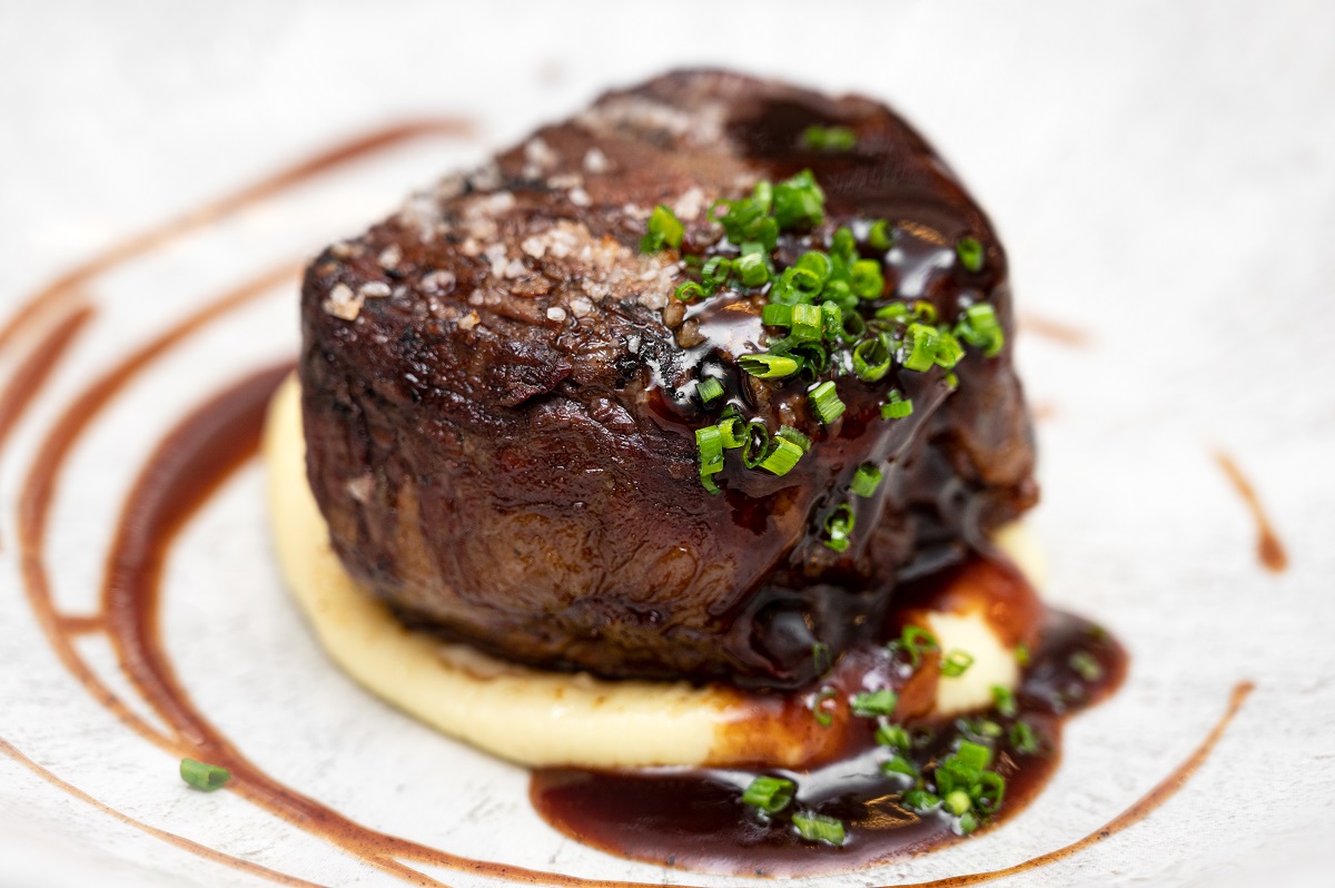 a round thck steak topped with chives and gravy
