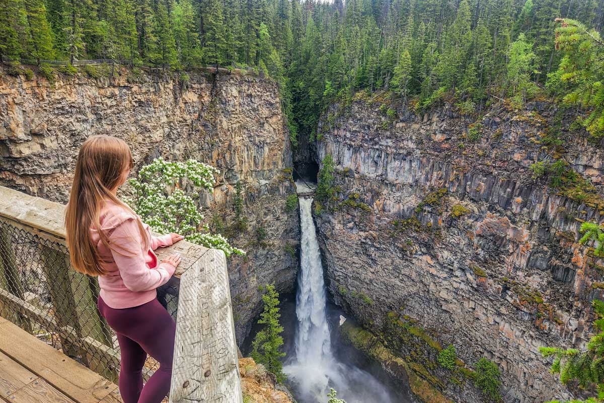 A lady stands on the viewpoint and looks at Spahats Creek Falls, Wells Gray