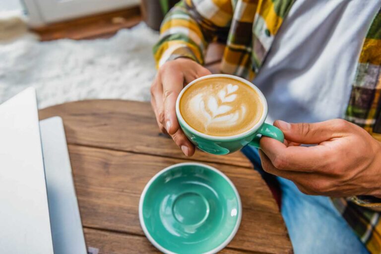 A person holds a coffee from a coffee shop in Vernon