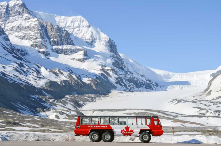 An Ice Explorer all-terrain vehicle parked with the Athabasca Glacier in the background on a summers day in Canada