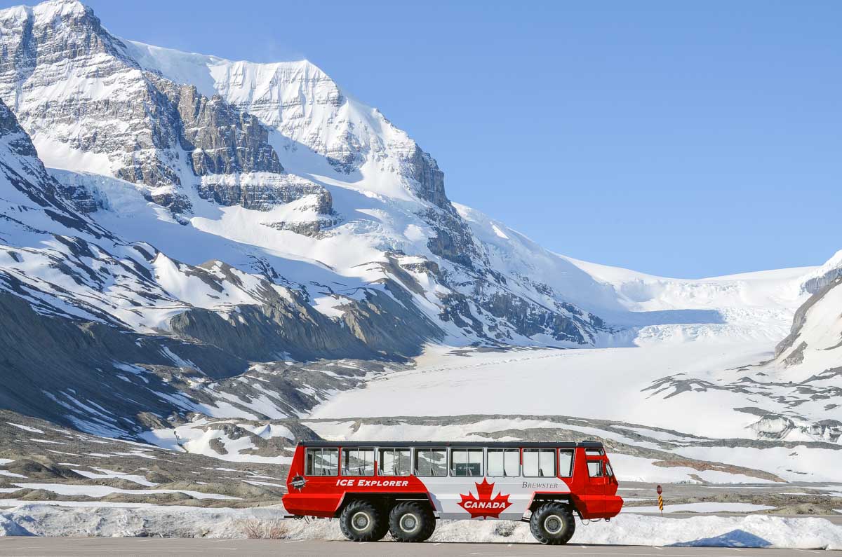 An Ice Explorer all-terrain vehicle parked with the Athabasca Glacier in the background on a summers day in Canada
