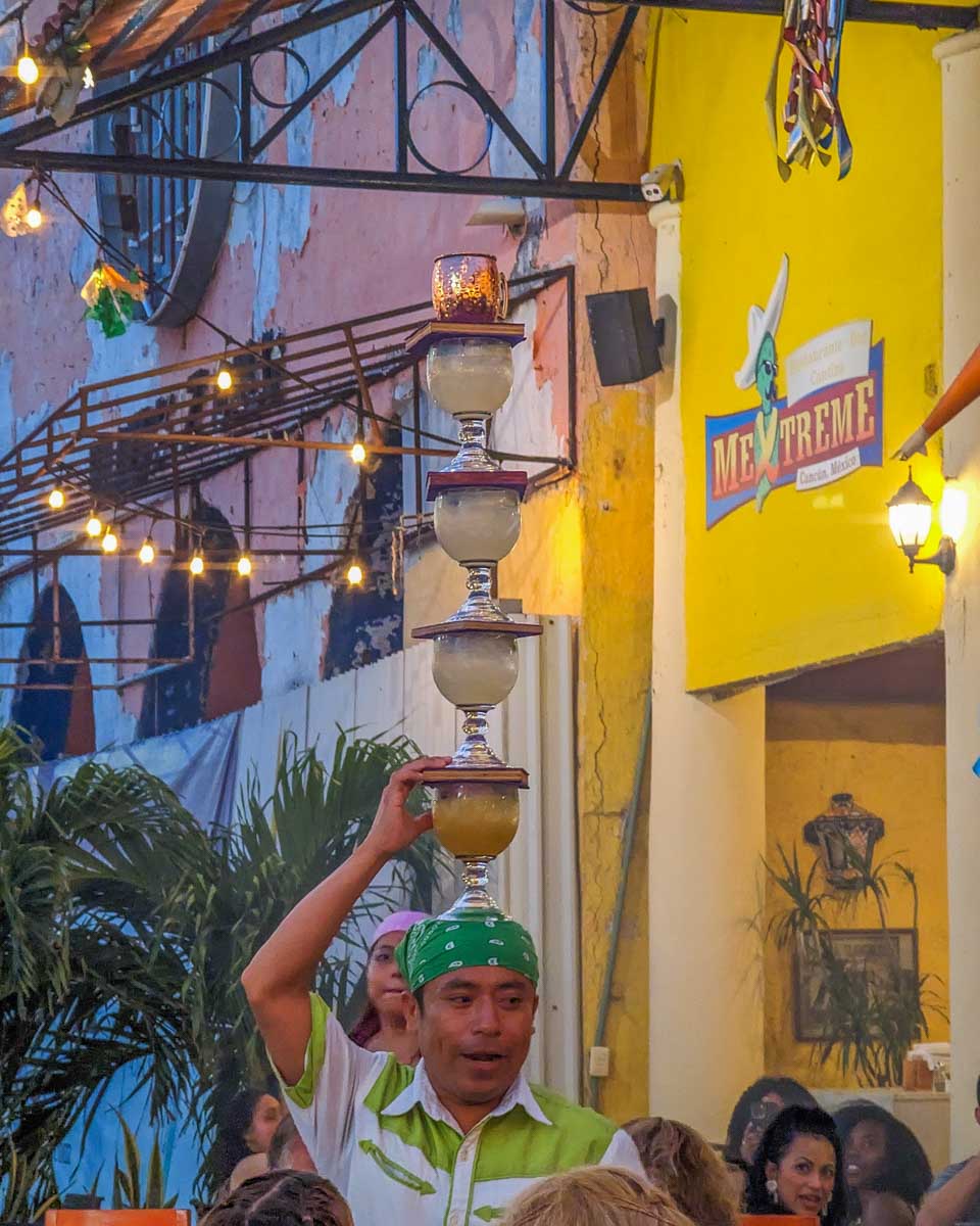 A waiter at Mextreme in Cancun carries 4 margaritas on his head